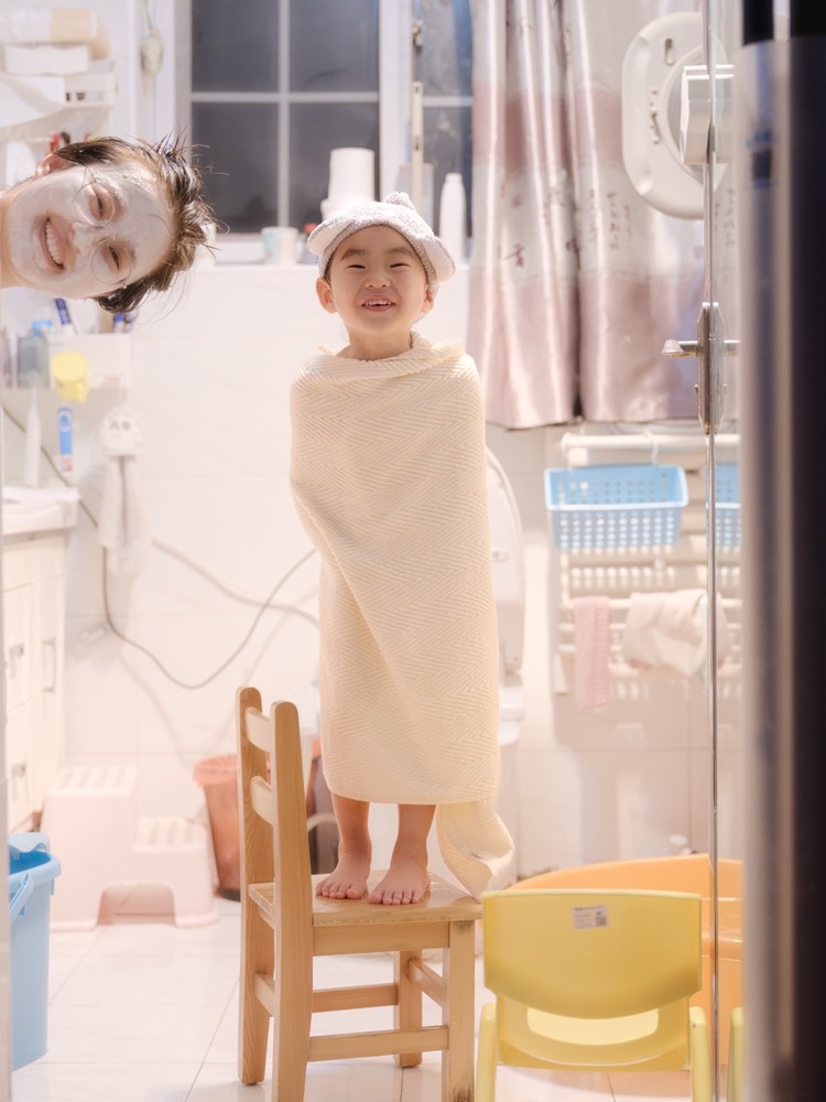 浴室里,母亲俯身照顾年幼的孩子